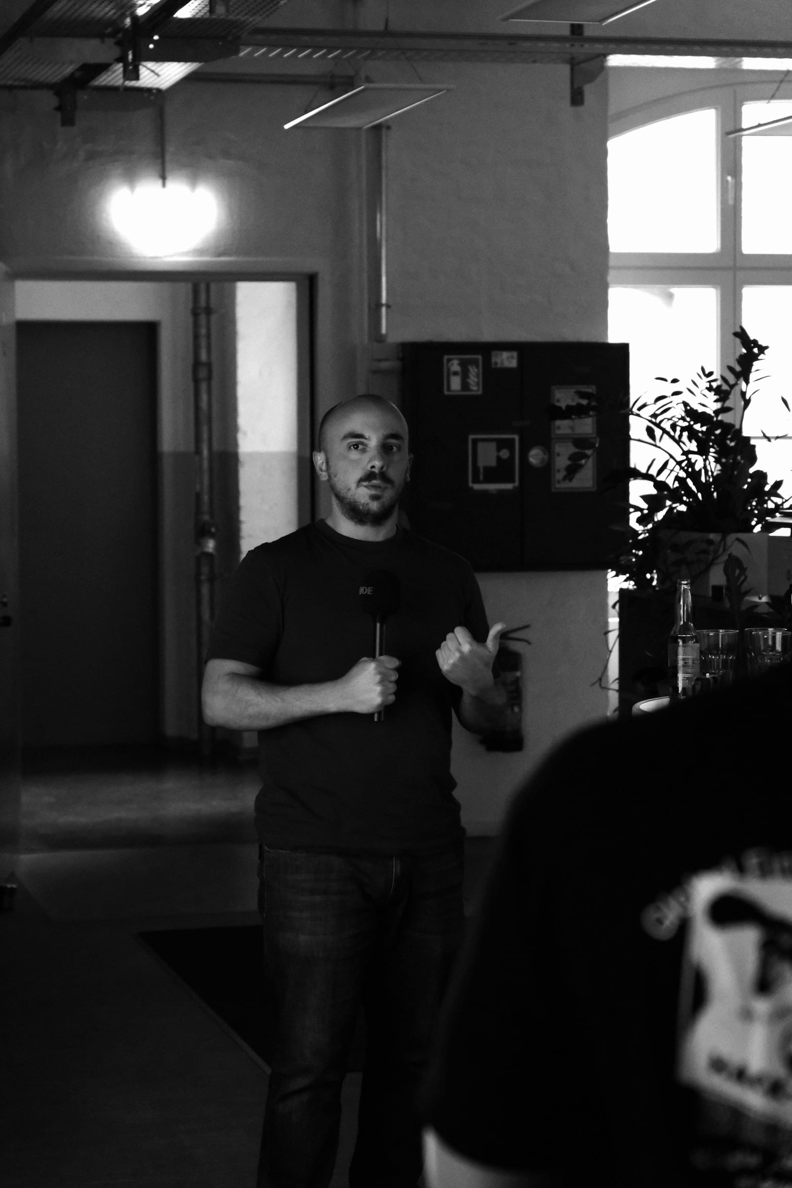 A speaker presenting with a microphone at the Berlin Finance Hackathon