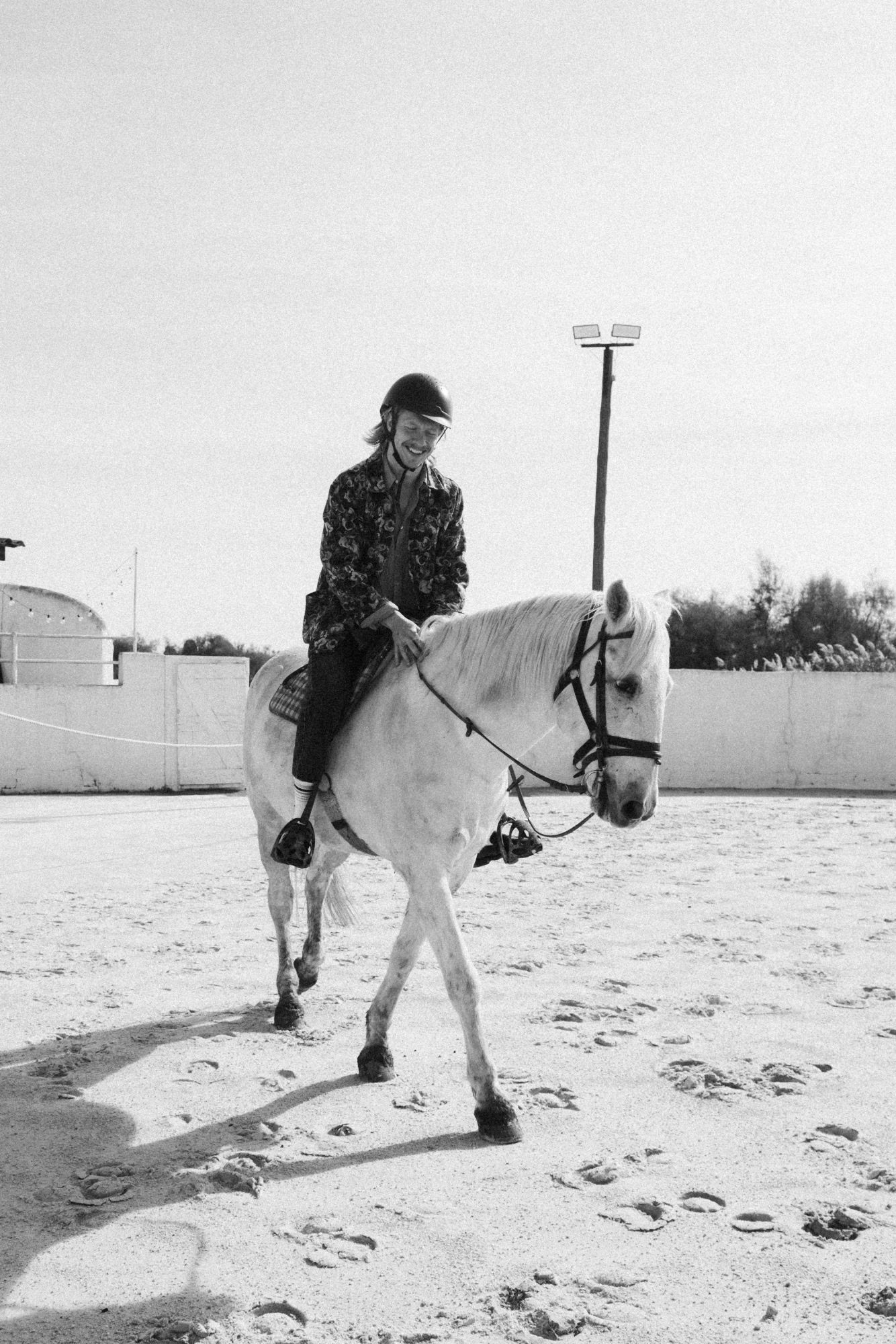 A Lighter in a riding helmet on a white horse, smiling