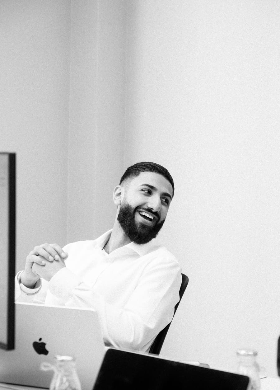 A teammate laughing during a conversation at his desk