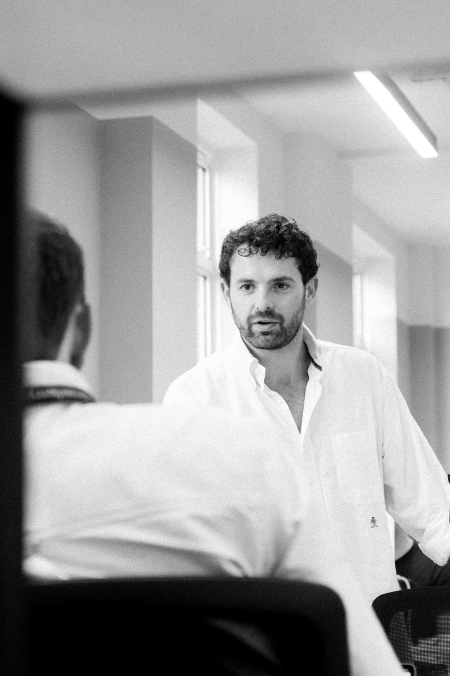 A teammate mid-conversation in a sunlit office hallway