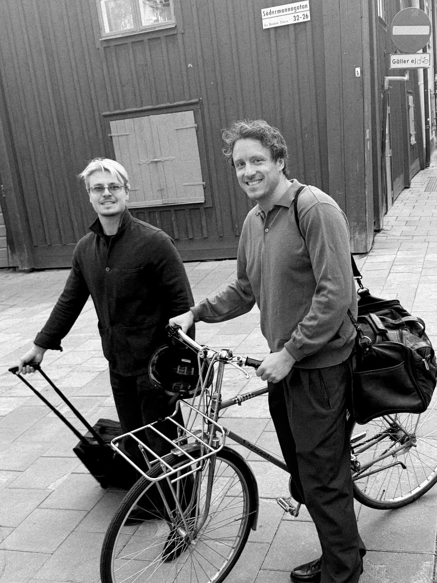 Two teammates walking a bike and luggage down a city street
