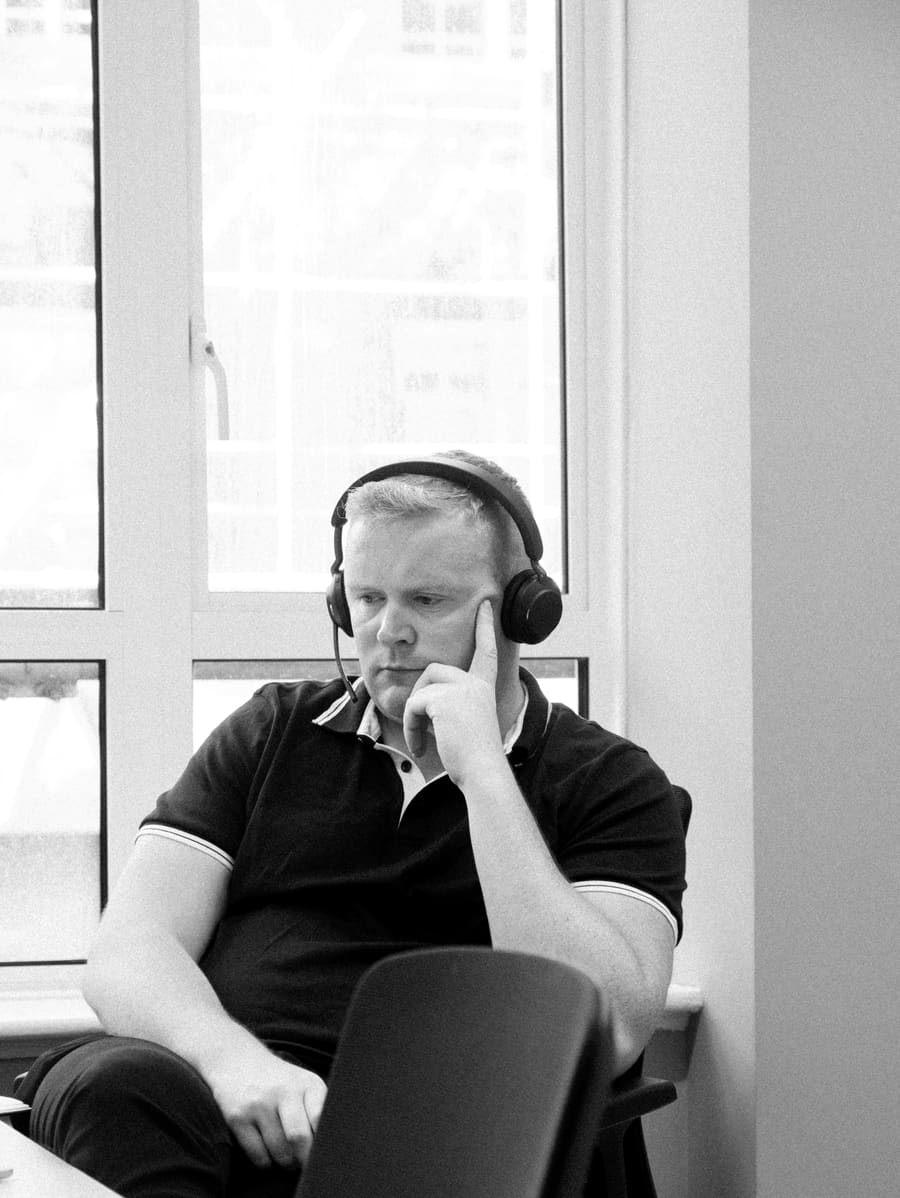 A teammate deep in focus with headphones on by a window