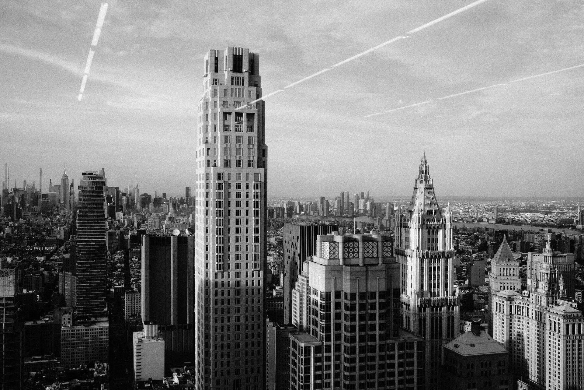 A city of towers seen from above, with contrails across the sky